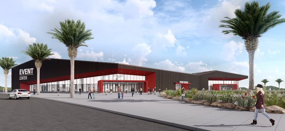 Modern event center with red and black exterior, large windows, and an entrance sign that reads "EVENT CENTER." Palm trees line the sidewalk, and people are walking around the area.