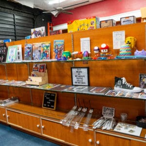 this is the inside of a comic store and has many items on display including cartoon characters, autographed shoes, jewelry, and Nintendo characters