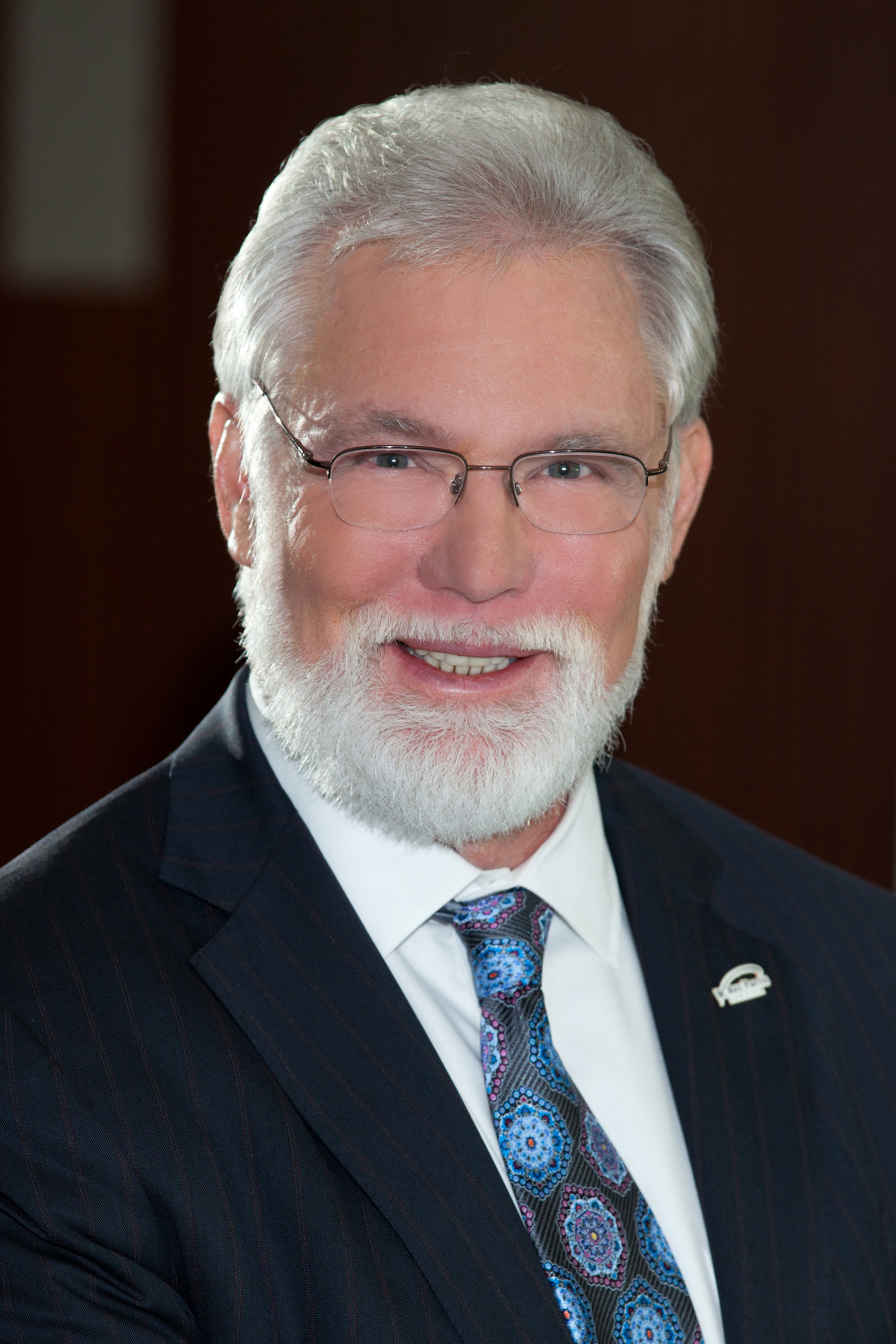 A smiling senior man in a business suit promoting Lancaster economic growth.