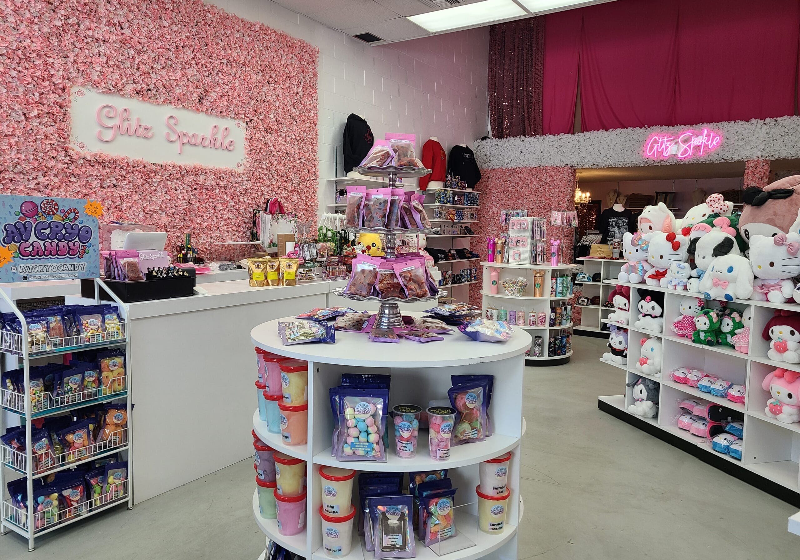 A pink-themed store interior with shelves displaying various toys, plushies, and colorful accessories. A neon "Glitz Sparkle" sign is on the wall.