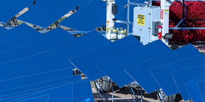 A vehicle labeled "Chariot" is operating among multiple rows of solar panels in a dry landscape.